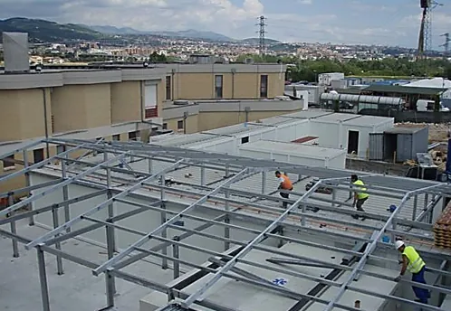 Operai al montaggio della struttura metallica di copertura sopra moduli prefabbricati