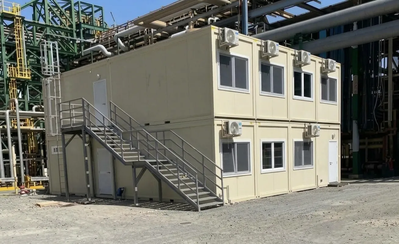 Edificio modulare a due piani con scala esterna e climatizzatori in un impianto industriale