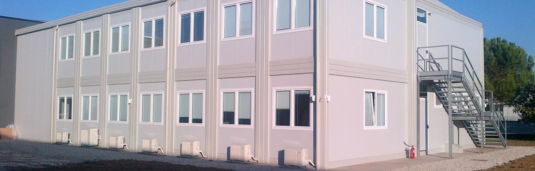 Edificio modulare a due piani con scala esterna metallica su area di cantiere