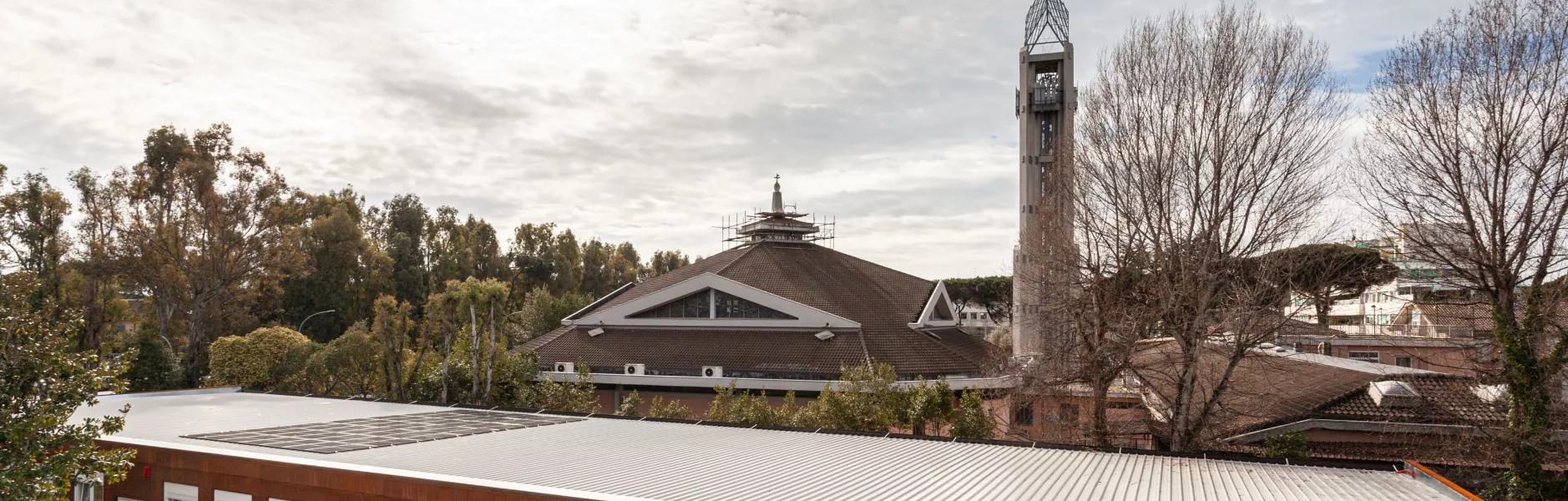 Edificio scolastico modulare con rivestimento in legno accanto a un campanile