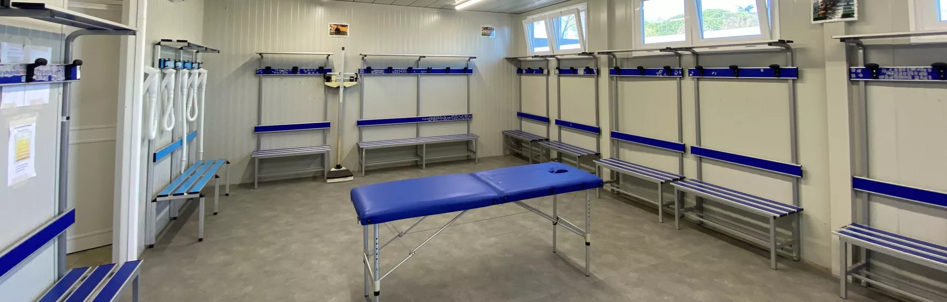 Interno di uno spogliatoio prefabbricato con panche e appendiabiti