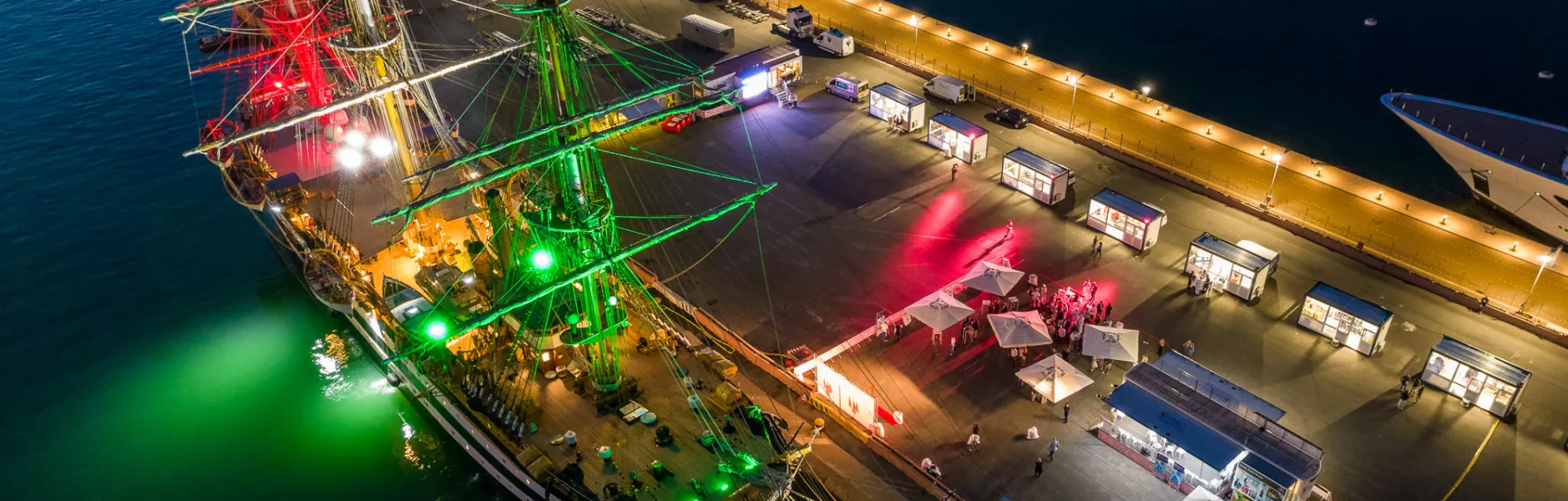 Veliero illuminato di notte con stand allestiti sulla banchina