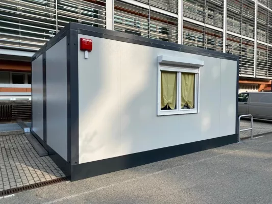 Monoblocco prefabbricato singolo posizionato nel piazzale di un edificio ospedaliero