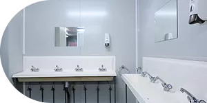 Interno di blocco sanitario con lavabi in fila e specchi a parete