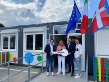 Consegna simbolica di una grande chiave davanti a un'aula modulare colorata