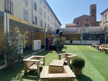 Area eventi con moduli gialli tavoli in legno e prato sintetico
