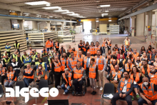 Numerosi lavoratori con gilet ad alta visibilità riuniti in un capannone