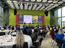 Sala conferenze con tavoli rotondi e pubblico davanti al palco durante una premiazione