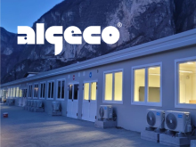 Edificio modulare con finestre illuminate al tramonto ai piedi della montagna